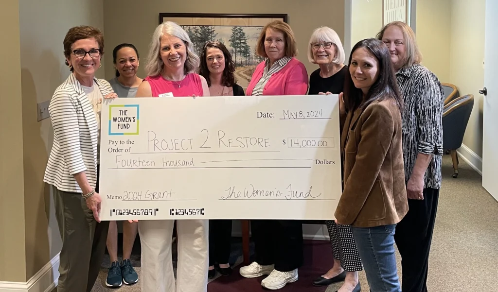 Women presenting a $14,000 grant check, illustrating grants for women in Topeka.