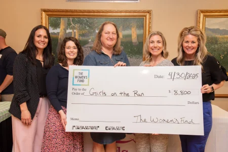 Five women presenting an $8,800 grant check to Girls on the Run, supporting grants for women in Topeka.