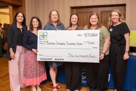 Six women presenting a $7,000 grant check to the Kansas Children’s Discovery Center, supporting women’s collective giving.