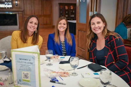 Attendees seated at a table featuring a collective giving sign, showcasing women’s collective giving group efforts.