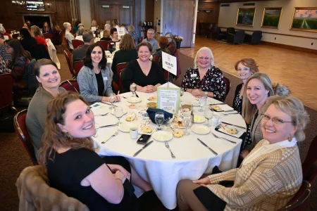 Guests seated at a reserved banquet table discussing impact and collaboration, reflecting women-led community impact.