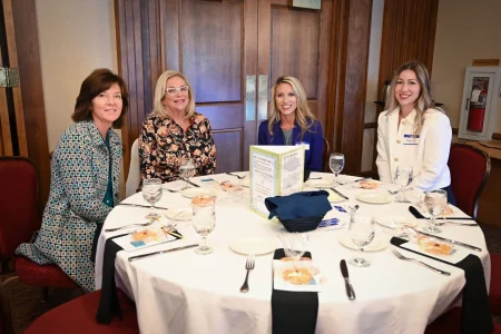 Four attendees seated at a banquet table during a community event, supporting women’s philanthropy in Topeka.